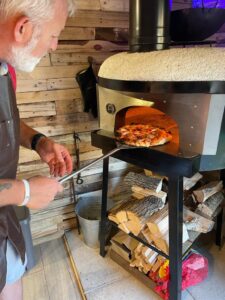 Mark taking a freshly cooked pizza out from the wood-fired pizza oven